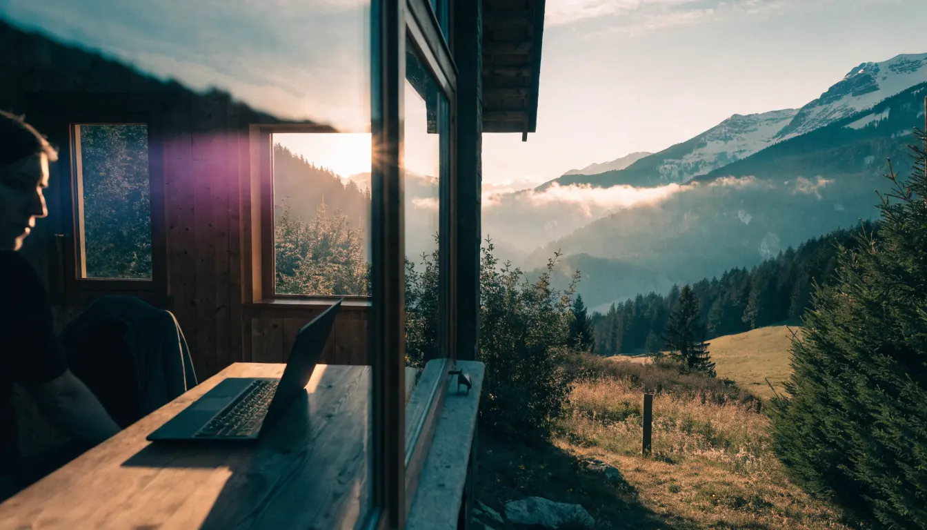 Alpines Chalet bei Sonnenaufgang, Laptop im Innenraum, Symbol für Datenschutz